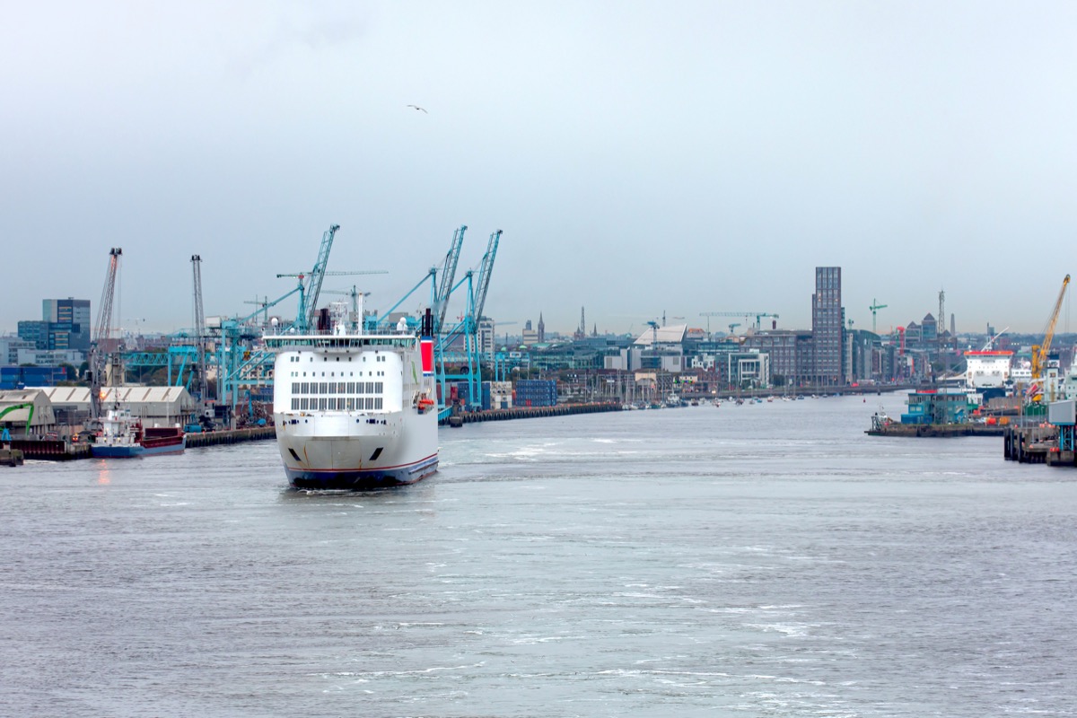 A ferry entering Dublin Port with harbour cranes and the Dublin skyline behind it